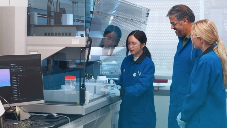 Researchers in a pharmaceutical lab working with automated drug discovery equipment